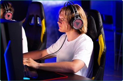 Een jongen met blond haar zit achter zijn computer en speelt geconcentreerd een spel.