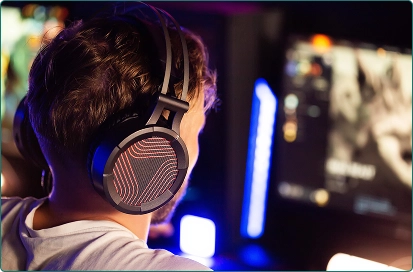 Een jongen met een koptelefoon op zit voor de computer en speelt een spel.