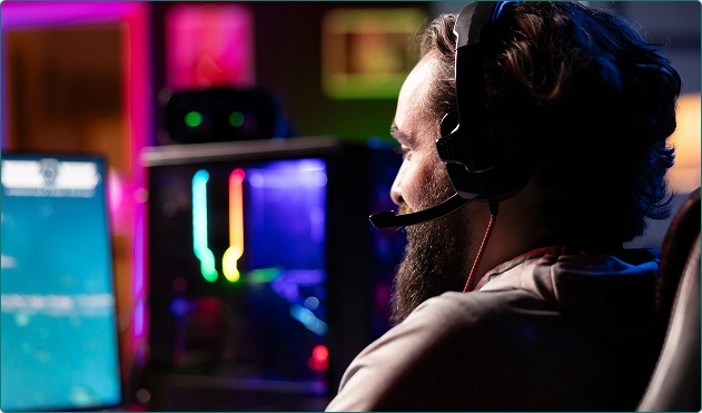 Een man zit met zijn rug naar ons toe achter de computer en speelt een spel.