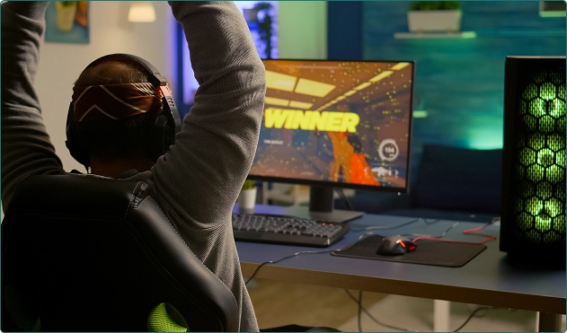 Een man zit met zijn rug naar ons toe achter de computer en speelt een spel.